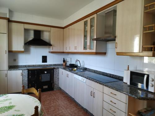 uma cozinha com armários de madeira e bancadas pretas em Vista Estrelada em Requeixo