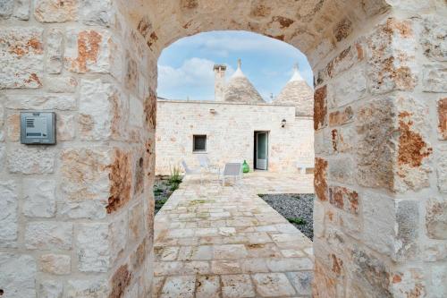 an archway in a stone wall with a building at Trulli in Vigna in Selva di Fasano