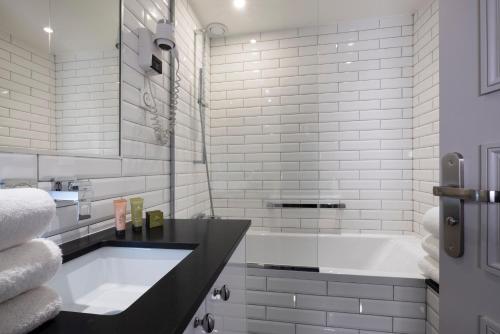 a white bathroom with a tub and a sink at Pavillon Monceau in Paris