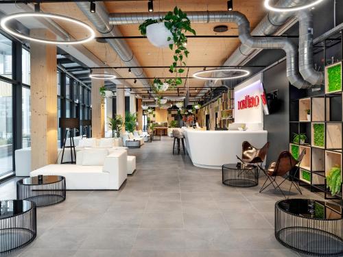 an office lobby with white couches and plants at DORMERO HoHo Wien in Vienna