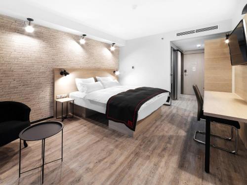 um quarto de hotel com uma cama e uma secretária em DORMERO Hotel Budapest em Budapeste