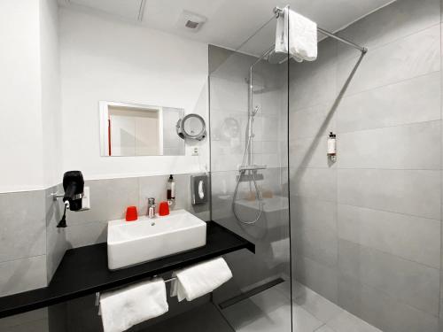 a bathroom with a sink and a shower at DORMERO Hotel Darmstadt in Darmstadt