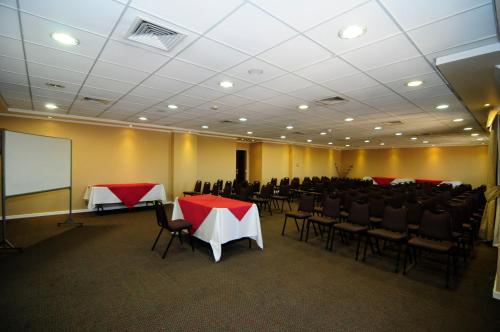 a conference room with tables and chairs and a screen at Hotel Diego De Almagro Calama in Calama