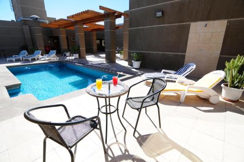 a patio with chairs and a table next to a pool at Hotel Diego De Almagro Calama in Calama