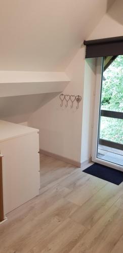 an attic room with a large window and white walls at La petite maison in Le Bosc-Roger-en-Roumois
