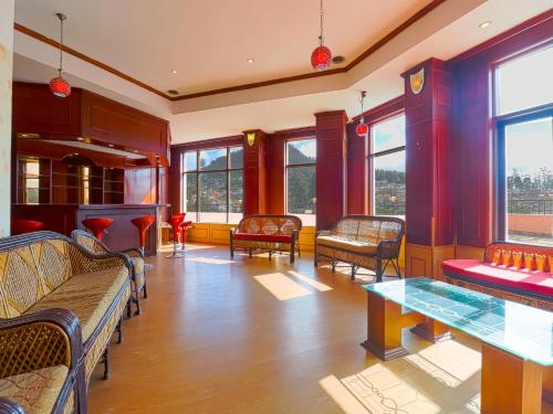 a room with chairs and a table and windows at The Byke Sunshine Grand in Ooty