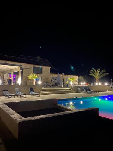 uma piscina à noite com cadeiras e um edifício em Suite Privative Jacuzzi Sauna de la Villa Del Castagnol em Saint-Nexans