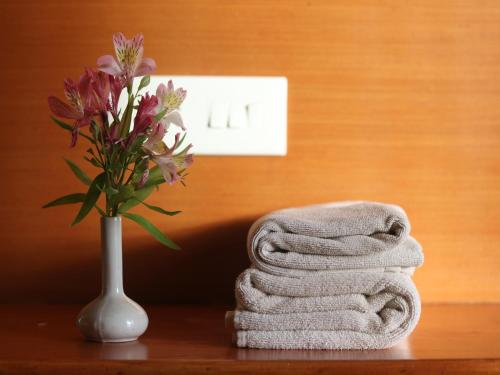 a pile of towels and a vase with flowers on a table at The Byke Sunshine Grand in Ooty