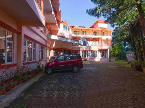 a small red car parked in front of a building at The Byke Sunshine Grand in Ooty