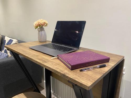 un ordenador portátil sentado en una mesa con un cuaderno en Gladstone Apartments by Bluebell Rooms, en Southampton