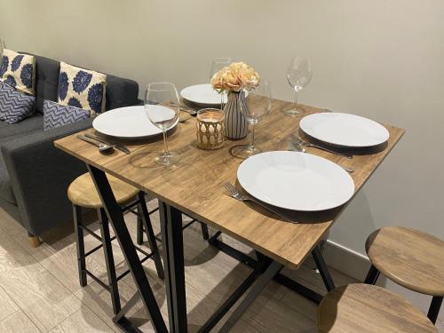 una mesa de madera con platos y copas de vino. en Gladstone Apartments by Bluebell Rooms, en Southampton