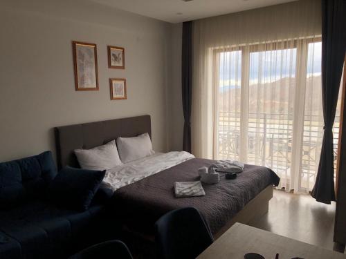 um quarto com uma cama, um sofá e uma janela em Snaer Milmari Apartman Kopaonik em Kopaonik