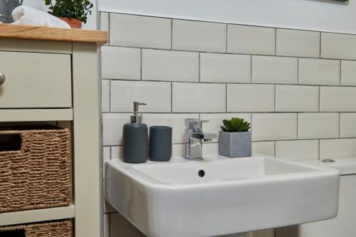 lavabo blanco en el baño con azulejos blancos en Delven House, Apartment 3, en Castle Donington