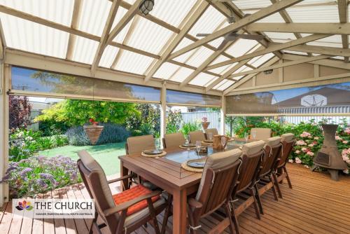 an outdoor dining room with a wooden table and chairs at 'THE CHURCH' Guest Home, Gawler Barossa Region in Willaston