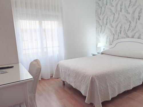 a white bedroom with a bed and a window at Hotel Florida in Albacete