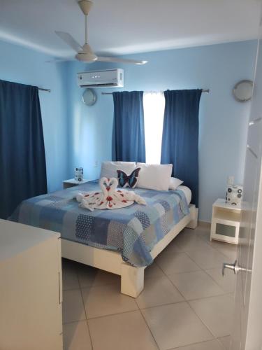 1 dormitorio con 1 cama con paredes azules y cortinas azules en La Fenice, Playa Popy, en Las Terrenas