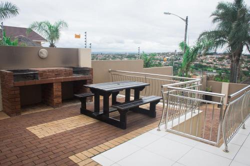 a patio with a table and bench on a balcony at Condo Villas in Durban