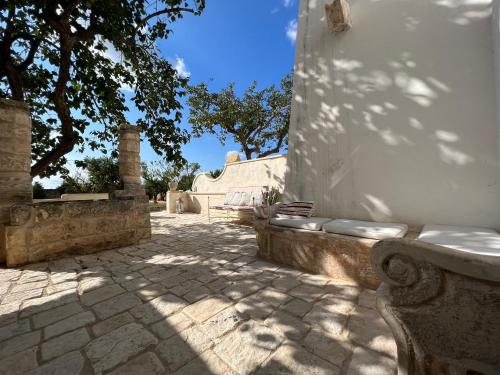 a stone courtyard with a bench and a tree at Tenuta Mosè Charming House&Relais Gallipoli in Gallipoli