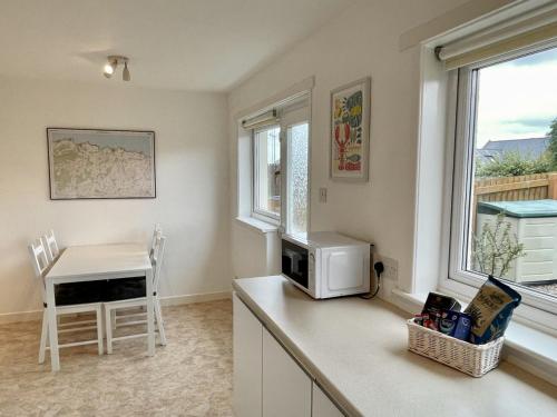 een keuken met een magnetron en een tafel en een raam bij Spacious 2 Bedroom Home in Picturesque Cullen in Cullen