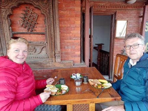Sunny Guest House and Cafe في بهاكتابور: يجلس رجل وامرأة على طاولة مع طبق من الطعام