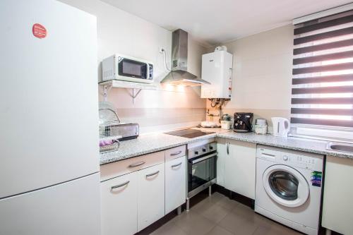 cocina blanca con lavadora y microondas en Serrallo Apartment, en Huétor Vega