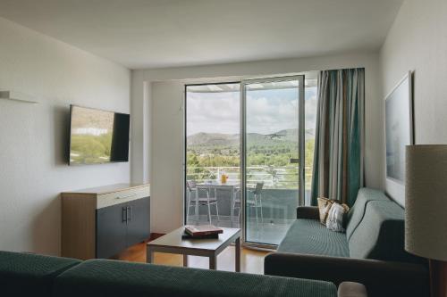 a living room with a couch and a window with a view at Hotel Ivory Playa Sports & Spa in Port d'Alcudia