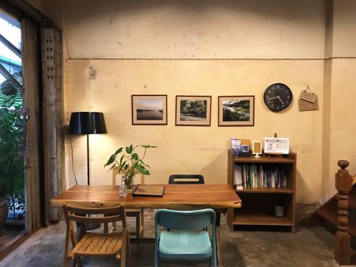 ein Esstisch mit Stühlen und einer Uhr an der Wand in der Unterkunft Boundary Hostel and Cafe in Surat Thani