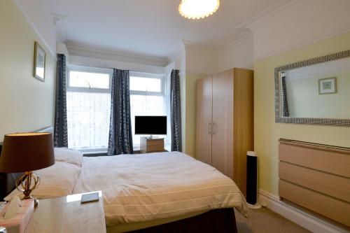 1 dormitorio con cama, ventana y TV en Brightwater family room for up to 3 people with shared facilities, en Scarborough