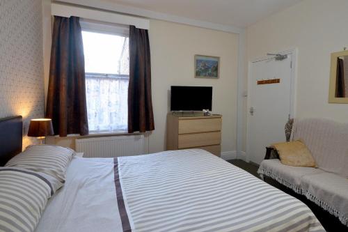 1 dormitorio con cama, sofá y ventana en Brightwater family room for up to 3 people with shared facilities, en Scarborough