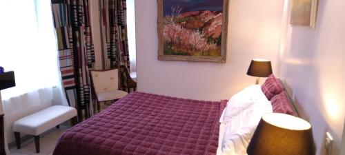 a small bedroom with a purple bed and a chair at Chambres et Tables d'hôtes du Puits d'Athie in Appoigny