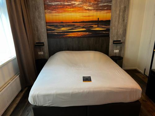 a bed in a room with a painting on the wall at Hotel Nap in West-Terschelling