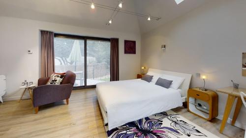 a bedroom with a large white bed and a chair at South Lodge in Milton Keynes