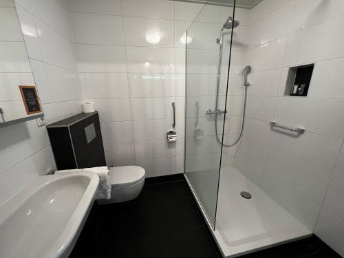 a bathroom with a shower and a toilet and a sink at Hotel Nap in West-Terschelling