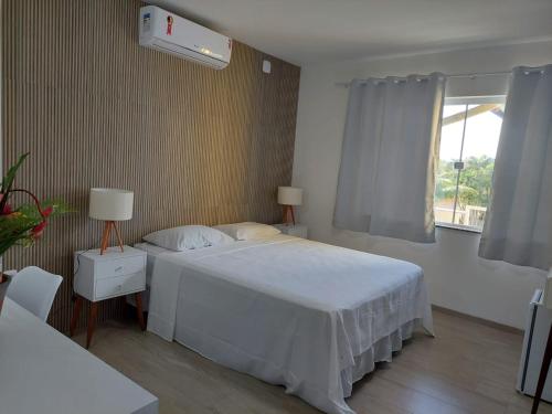 a bedroom with a white bed and a window at Pousada Vitória in Ilhéus