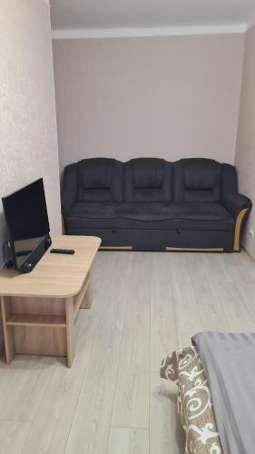 un soggiorno con divano nero e tavolo di Квартира 1-кімнатна в центрі Миргорода. a Myrhorod