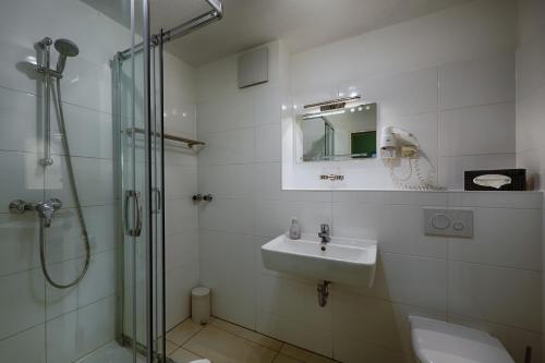 a white bathroom with a sink and a shower at Hotel Sophienhof in Königs Wusterhausen