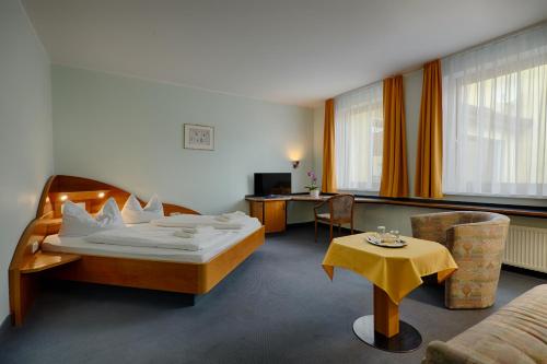 a hotel room with a bed and a table at Hotel Sophienhof in Königs Wusterhausen