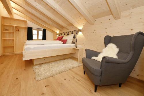 een slaapkamer met een bed en een stoel in een kamer bij Chalet 14 in Sankt Gallenkirch