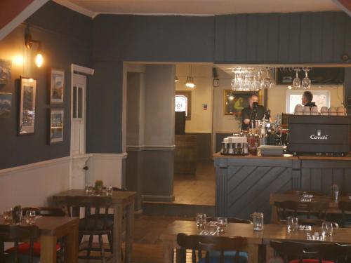 a restaurant with tables and a bar with a bartender at The Fox and Hounds in Whittlebury
