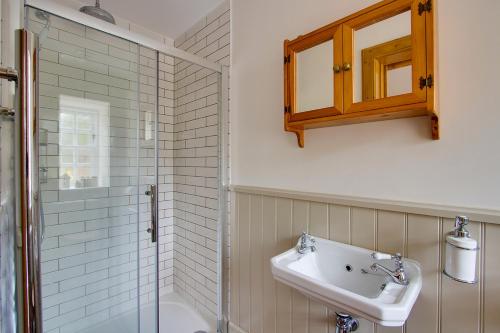 La salle de bains est pourvue d'un lavabo et d'une douche. dans l'établissement Balgavies Home Farm - Cottage, à Forfar