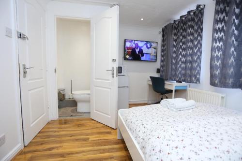 a bedroom with a bed and a desk and a toilet at Fabulous Room with en-suite bathroom and shared kitchen in Thamesmead