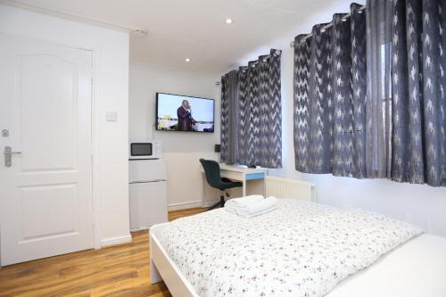 een slaapkamer met een bed, een bureau en een televisie bij Fabulous Room with en-suite bathroom and shared kitchen in Thamesmead