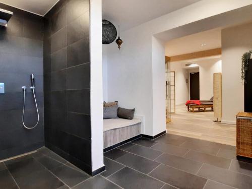 a bathroom with a shower and a bench in a room at DORMERO Hotel Deggendorf in Deggendorf