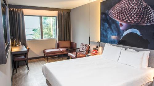 une chambre d'hôtel avec un lit et un grand tableau dans l'établissement Radisson RED London Greenwich The O2, à Londres