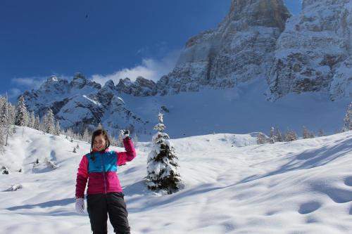 a woman standing in the snow with a christmas tree at Hotel B&B Lorenzini Ski in Selva di Cadore