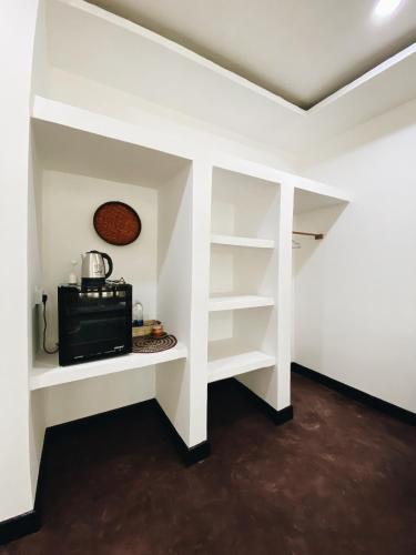 a kitchen with white shelves and a microwave in a room at Crystal Beach Nungwi in Nungwi
