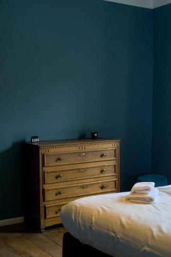 a bedroom with a wooden dresser and a blue wall at Château de la Chapelle in Anthisnes