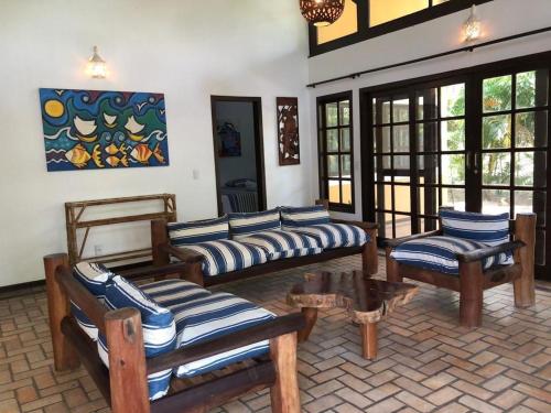 - un salon avec des canapés, une table et des fenêtres dans l'établissement Holiday Villa Praia da Pipa-5 Suites,Areá Gourmet by PipaCharme, à Pipa
