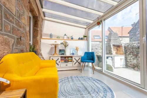 un salon avec un canapé jaune et un fauteuil bleu dans l'établissement Lovely Normandy un havre de paix en Bord de Mer, à Fermanville