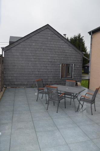 a patio with a table and chairs in front of a brick wall at La petite maison in Neufchâteau